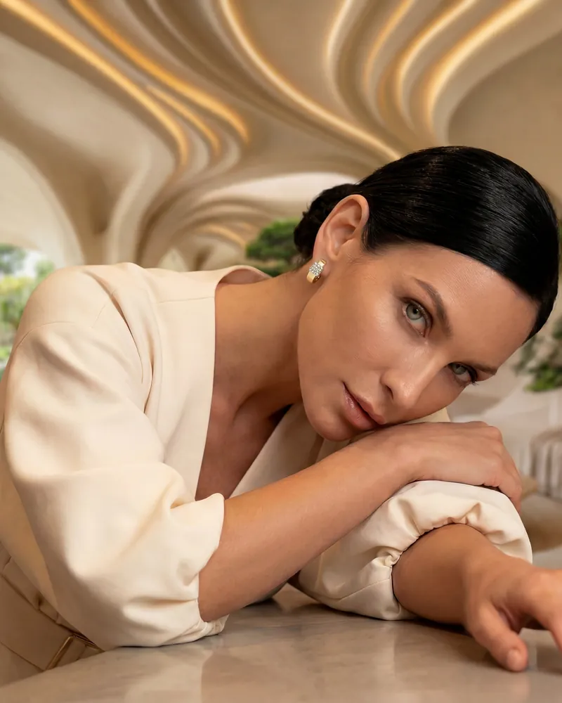 AI product photo: a model in a white blouse with earrings, resting on her hand